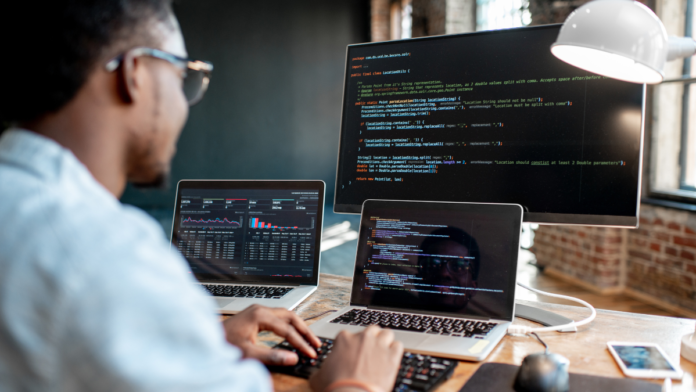 man facing multiple screens coding with tools